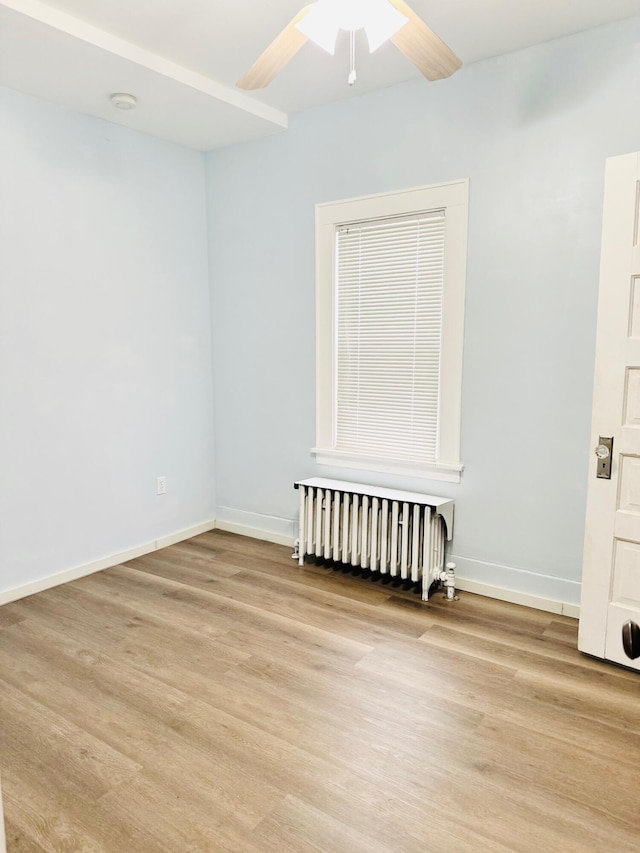 unfurnished room featuring radiator heating unit, ceiling fan, and light hardwood / wood-style flooring