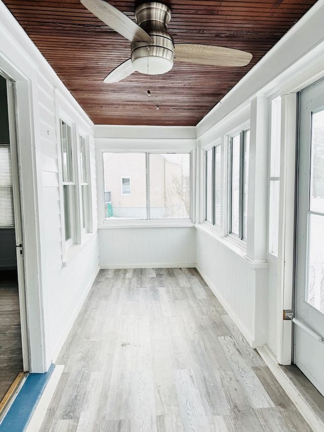 unfurnished sunroom featuring a healthy amount of sunlight, wooden ceiling, and ceiling fan