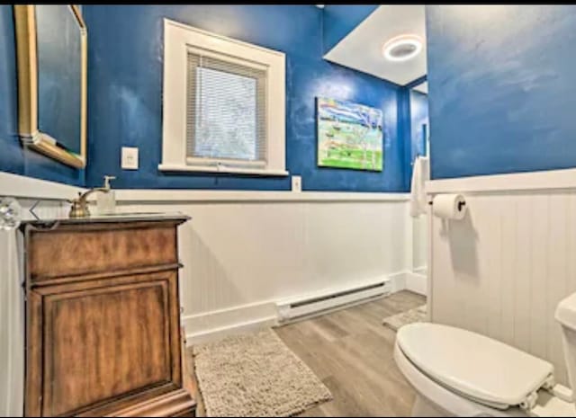 bathroom with hardwood / wood-style flooring, a baseboard radiator, vanity, and toilet