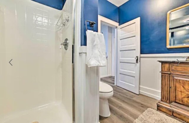 bathroom with wood-type flooring, a shower, and toilet