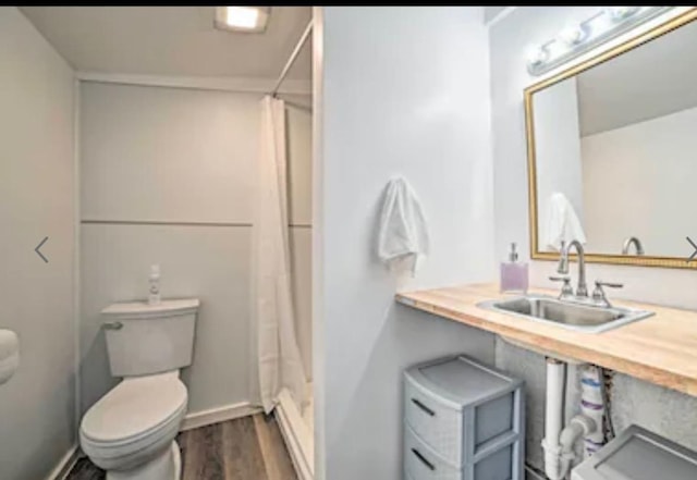 bathroom featuring sink, curtained shower, toilet, and hardwood / wood-style flooring