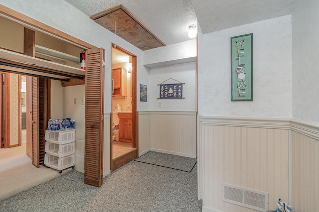 hallway with light carpet and a textured ceiling