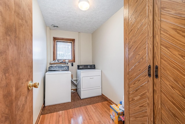 washroom featuring wood-type flooring, washer and dryer, and a textured ceiling