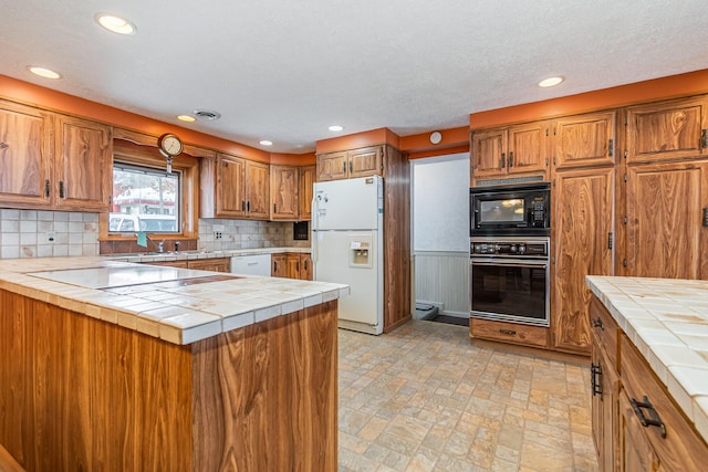 kitchen with tile counters, backsplash, a textured ceiling, and black appliances