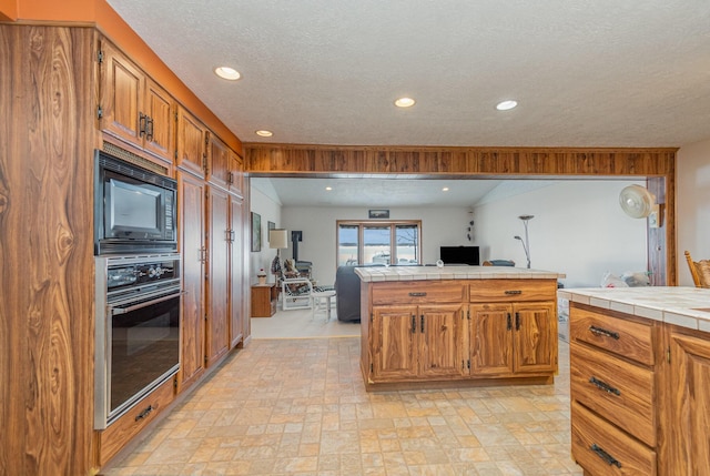 kitchen featuring built in microwave, stainless steel oven, tile counters, and a textured ceiling