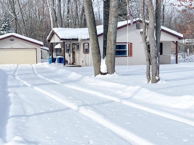 view of snow covered exterior featuring a garage and an outdoor structure