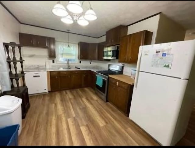 kitchen with sink, appliances with stainless steel finishes, an inviting chandelier, decorative light fixtures, and light wood-type flooring