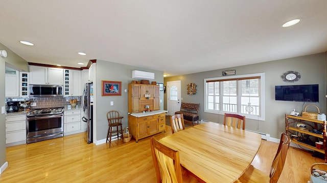 dining space with light wood finished floors, a wall unit AC, recessed lighting, and baseboards