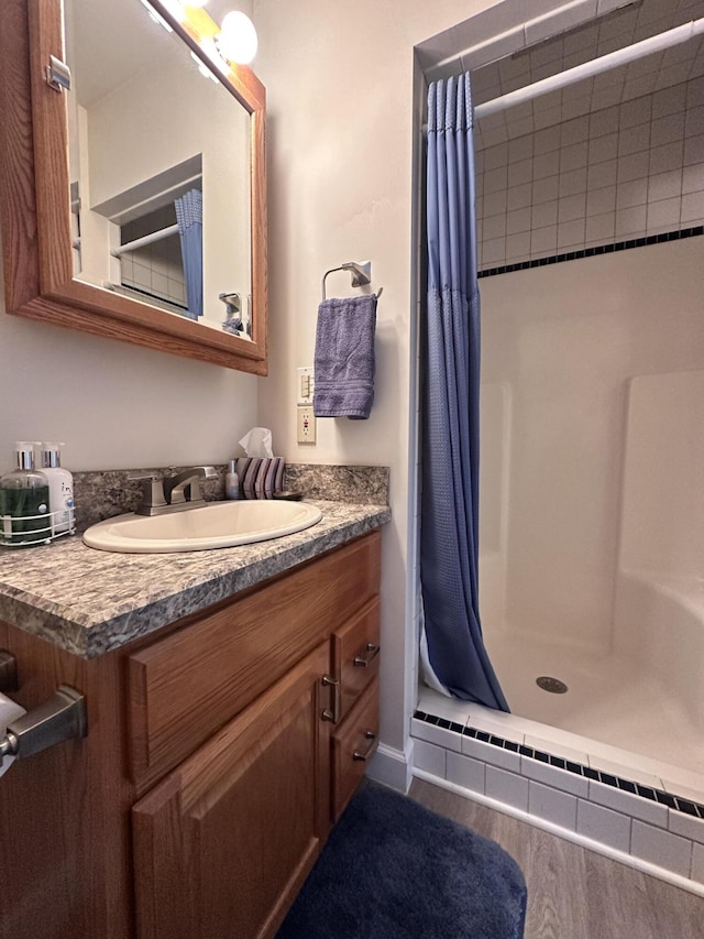 bathroom featuring wood finished floors, a shower stall, and vanity