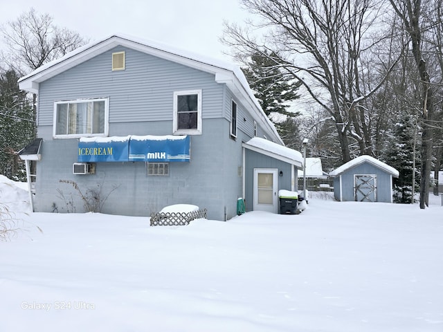 view of snow covered exterior with a shed