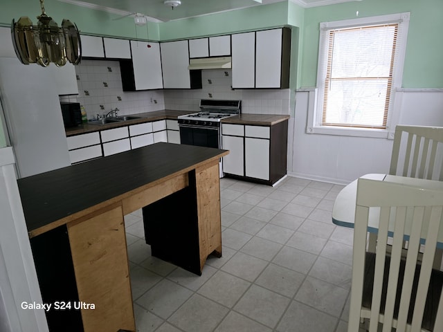 kitchen with sink, light tile patterned floors, tasteful backsplash, range with gas stovetop, and white cabinets