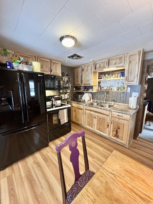 kitchen with sink, light stone counters, light wood-type flooring, light brown cabinets, and black appliances