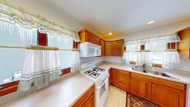 kitchen featuring recessed lighting, light countertops, brown cabinetry, a sink, and white appliances