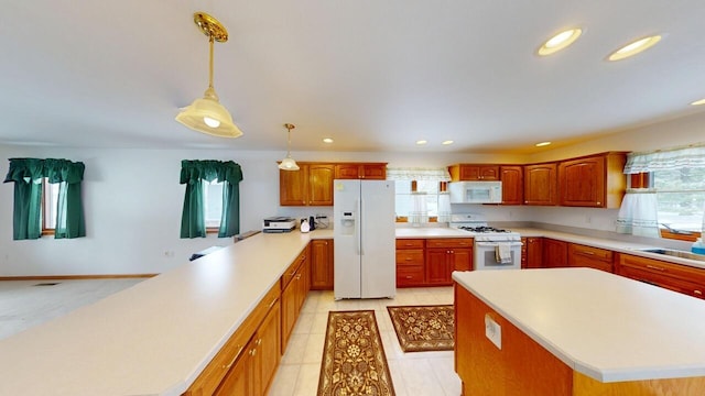 kitchen with white appliances, light countertops, a kitchen island, and decorative light fixtures