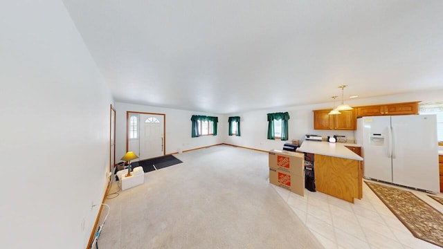 kitchen with white refrigerator with ice dispenser, open floor plan, a center island, light countertops, and pendant lighting