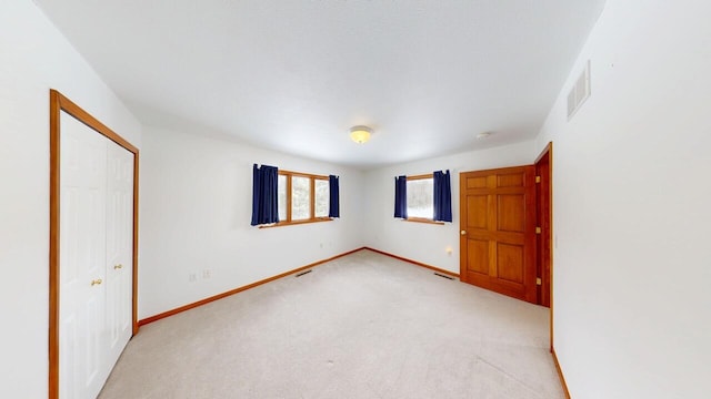 spare room with baseboards, visible vents, and light colored carpet