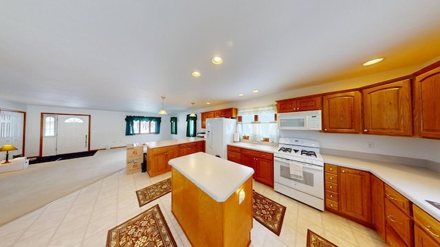 kitchen with light countertops, white appliances, a center island, and pendant lighting