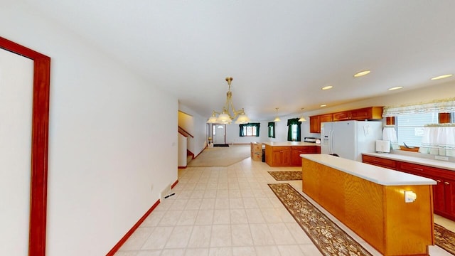 kitchen with open floor plan, hanging light fixtures, light countertops, a center island, and white fridge with ice dispenser