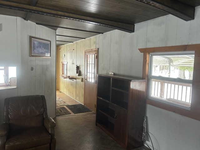 hall featuring beamed ceiling and wood walls