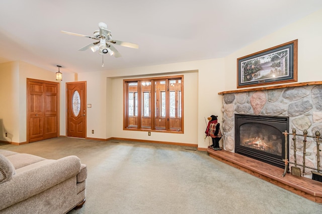 living room featuring light carpet, ceiling fan, baseboards, and a stone fireplace