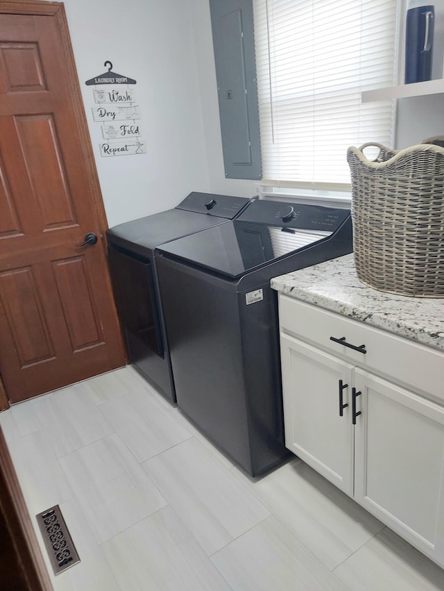 washroom with cabinets, washing machine and clothes dryer, and electric panel