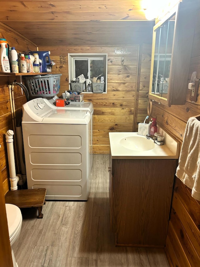 interior space featuring laundry area, wood walls, separate washer and dryer, and wood finished floors