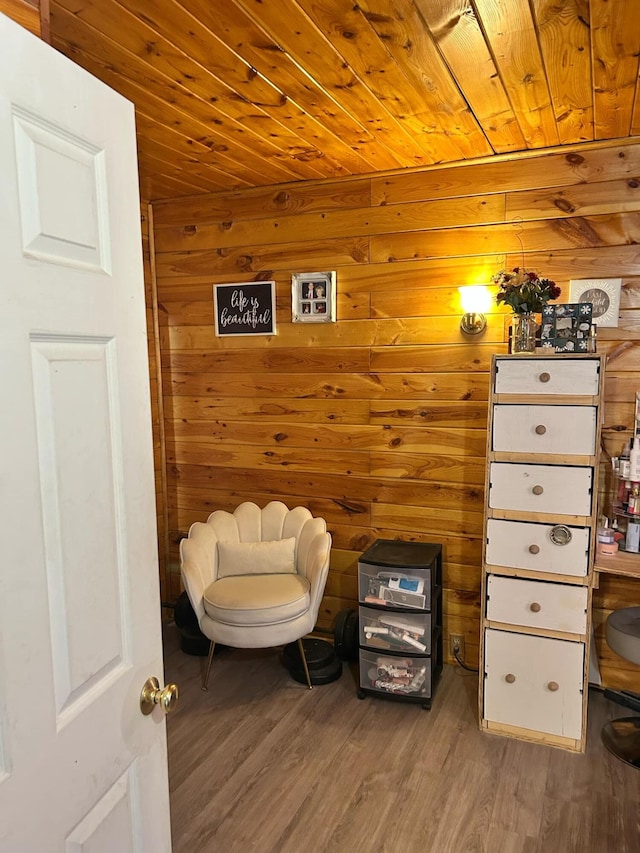 sitting room featuring light wood-type flooring, wood walls, and wood ceiling