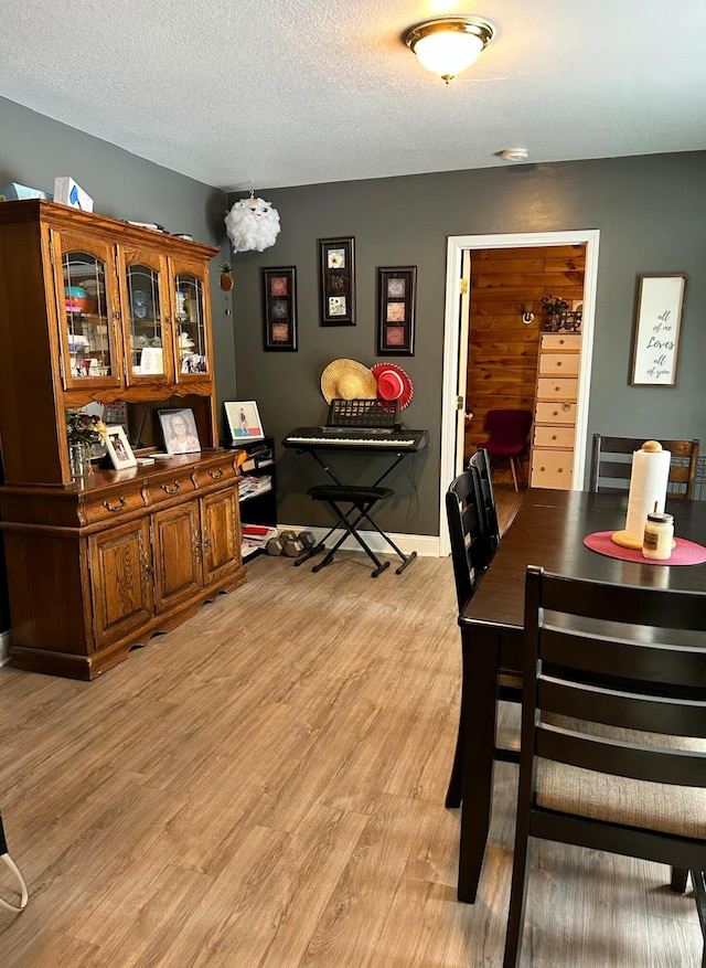 dining room featuring a textured ceiling, baseboards, and light wood-style floors