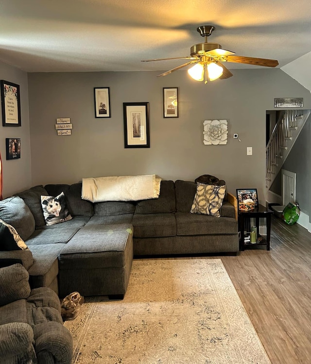 living area featuring a ceiling fan, stairway, and wood finished floors