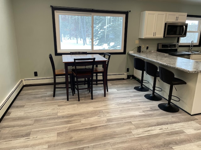 kitchen featuring light hardwood / wood-style flooring, sink, stainless steel appliances, white cabinets, and light stone countertops