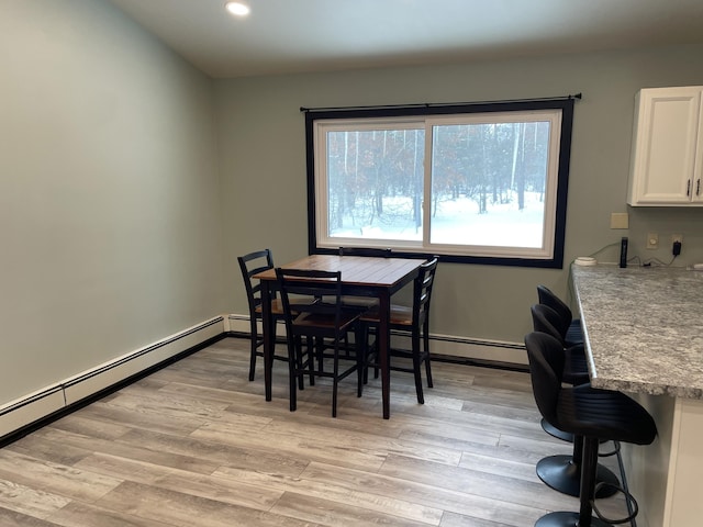 dining area with light hardwood / wood-style flooring and a baseboard heating unit