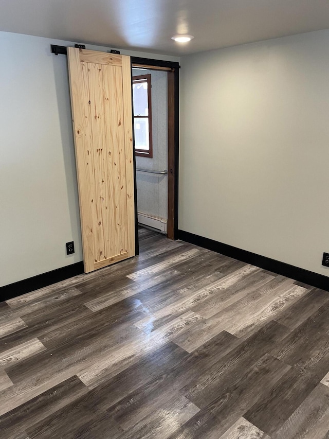 spare room with baseboard heating and dark hardwood / wood-style flooring