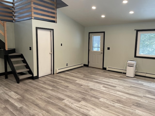 entryway with light wood-type flooring, vaulted ceiling, and a baseboard heating unit