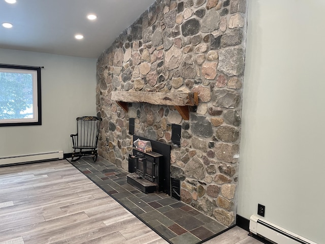 living room with a wood stove, a baseboard radiator, and hardwood / wood-style floors