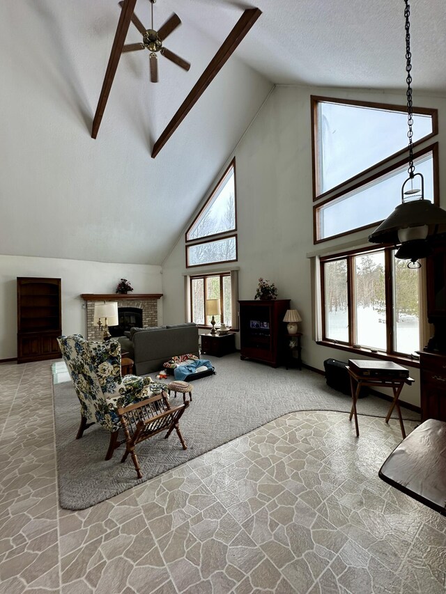 carpeted living room with stone flooring, high vaulted ceiling, a textured ceiling, and a glass covered fireplace