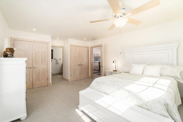 bedroom with baseboards, light colored carpet, ensuite bath, two closets, and recessed lighting