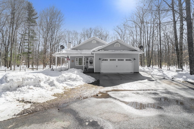 view of front of home with a porch, concrete driveway, a chimney, and an attached garage