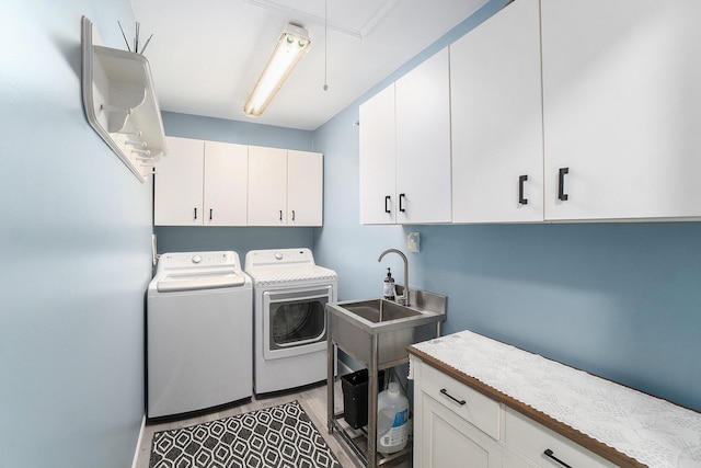 laundry room featuring cabinet space, attic access, a sink, and washing machine and clothes dryer