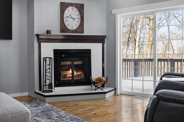 room details with baseboards, a tiled fireplace, and wood finished floors