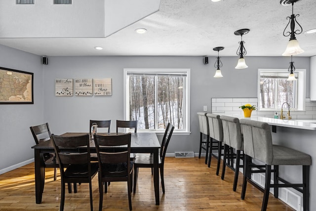 dining space featuring a textured ceiling, recessed lighting, wood finished floors, visible vents, and baseboards