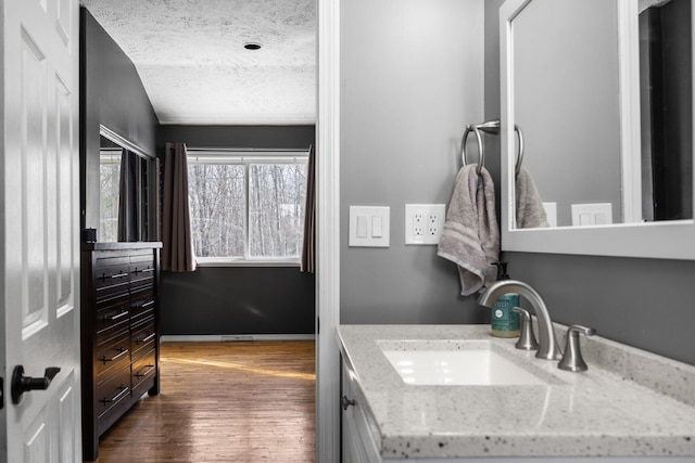 bathroom with a textured ceiling, wood finished floors, vanity, and baseboards