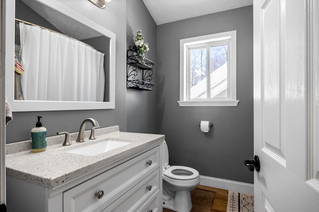 full bath featuring a textured ceiling, toilet, wood finished floors, vanity, and baseboards