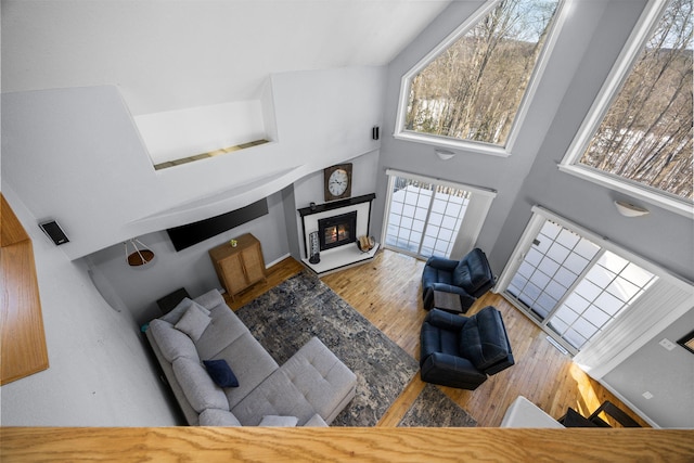 living area featuring a glass covered fireplace, a towering ceiling, and wood finished floors