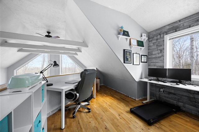 home office featuring plenty of natural light, lofted ceiling with beams, a textured ceiling, and wood finished floors