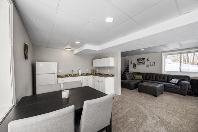 dining space featuring recessed lighting, light colored carpet, stairway, and a drop ceiling