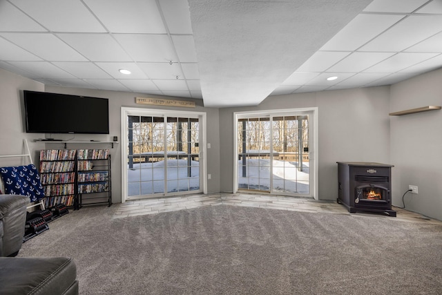 carpeted living area with a paneled ceiling, a lit fireplace, and recessed lighting