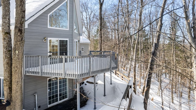 snow covered house featuring a wooden deck