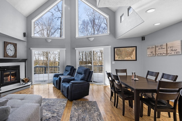 dining space featuring light wood-type flooring, a glass covered fireplace, plenty of natural light, and recessed lighting