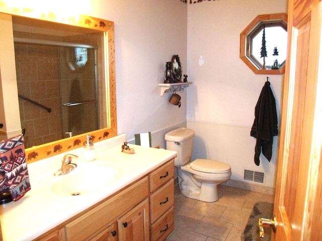 bathroom with toilet, tiled shower, vanity, and visible vents