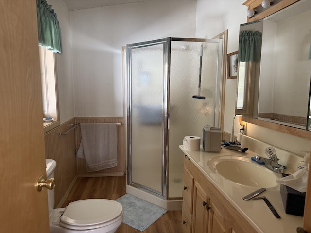 full bath featuring a stall shower, toilet, a wainscoted wall, wood finished floors, and vanity